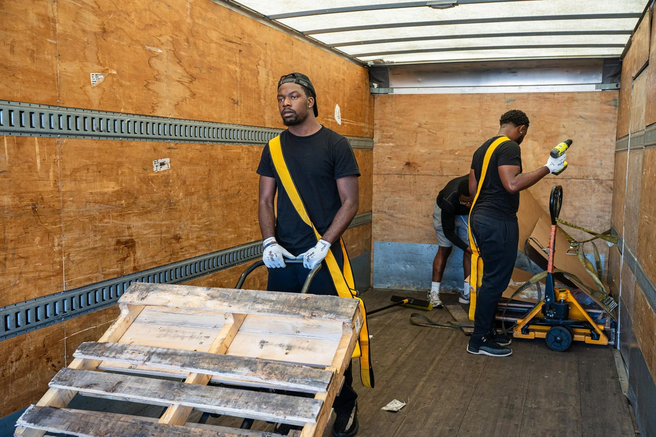 Haul Yeah Moving crew loading a wooden pallet with a pallet jack inside a 26-ft moving truck